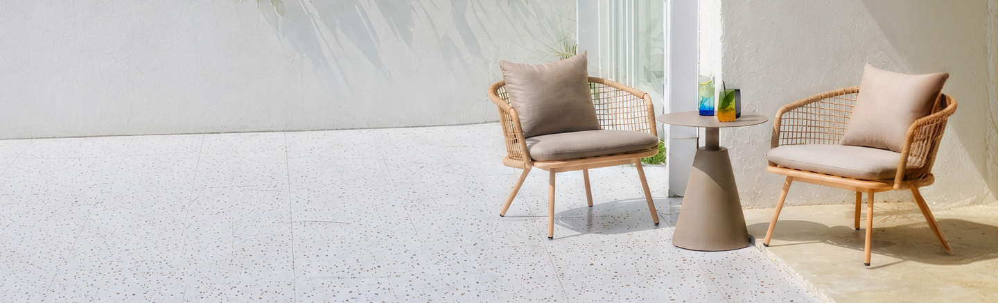 Two woven lounge chairs and a side table on a sunlit patio